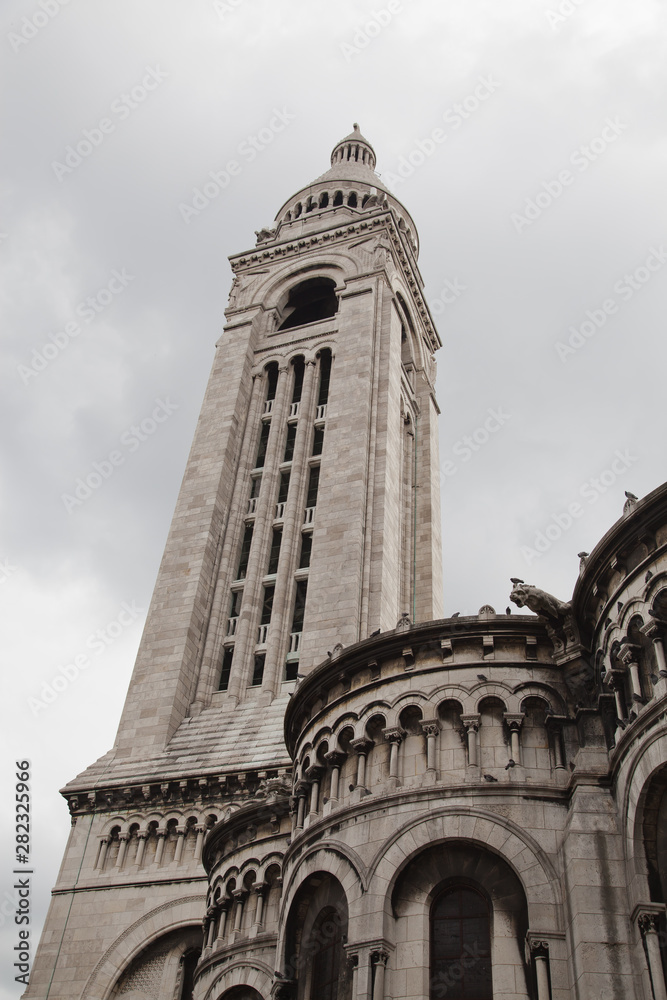 PARIS, FRANCE - MAY 30, 2014: Tourists stroll in Montmartre near Basilica Sacre Coeur (designed by Paul Abadie, 1914) - Roman Catholic Church and minor basilica, dedicated to Sacred Heart of Jesus.