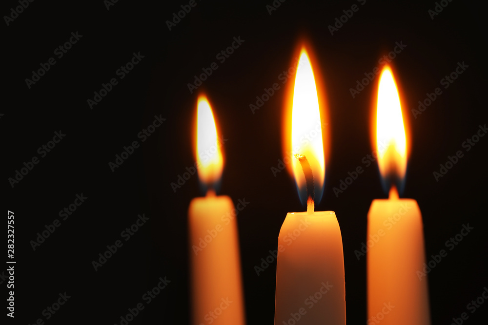Burning candles on dark background, space for text. Symbol of sorrow Burning candles on dark background, space for text. Symbol of sorrow