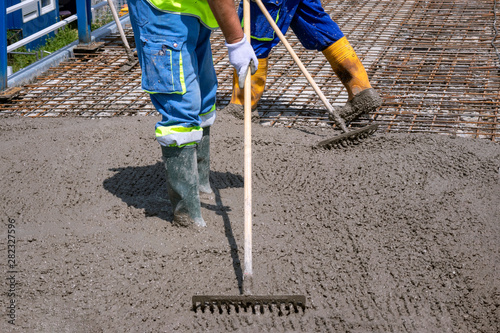 Construction worker spreading freshly poured concrete mix on the bridge with rake, repair sidewalk on bridge in Zagreb, Croatia