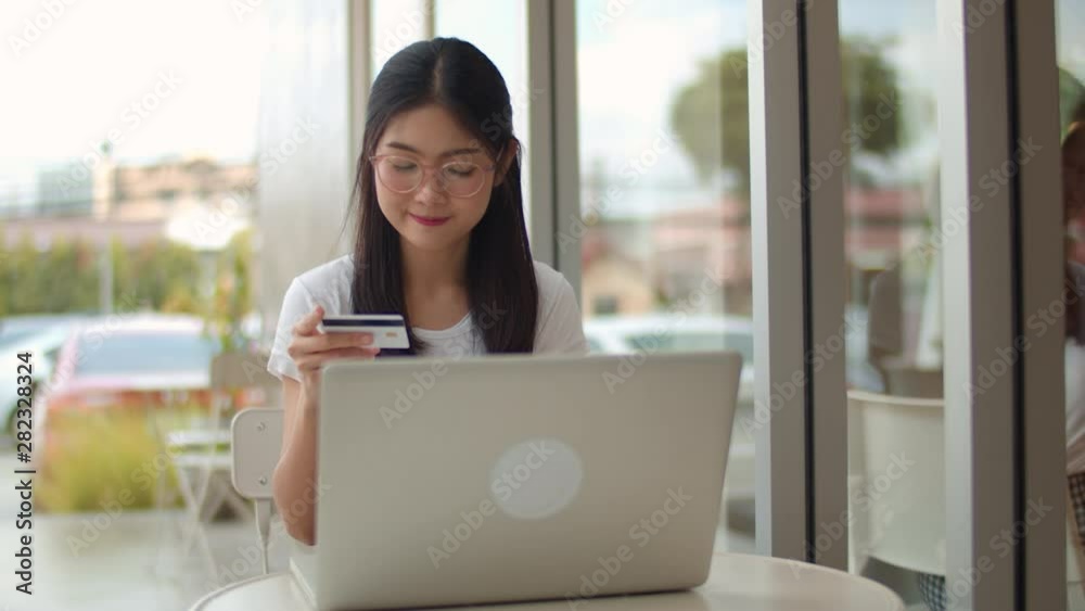 Freelance Asian women online shopping at coffee shop. Young Asia Girl using laptop, credit card buy and purchase e-commerce on internet on table at an outdoor cafe in evening concept. Slow motion Freelance Asian women online shopping at coffee shop. Young Asia Girl using laptop, credit card buy and purchase e-commerce on internet on table at an outdoor cafe in evening concept. Slow motion