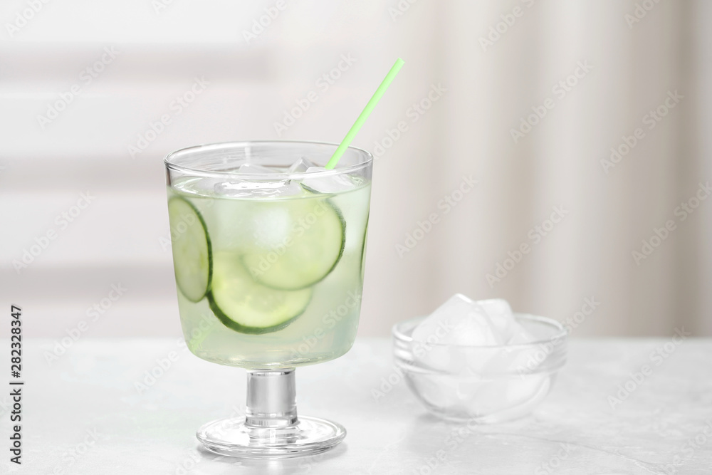 Glass of tasty cucumber martini cocktail with ice on table against indoors, space for text Glass of tasty cucumber martini cocktail with ice on table against indoors, space for text