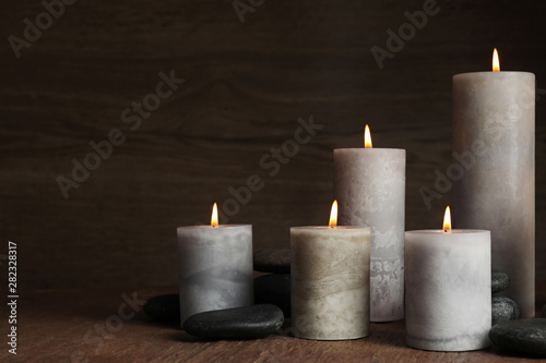 Burning candles and spa stones on wooden table  space for text