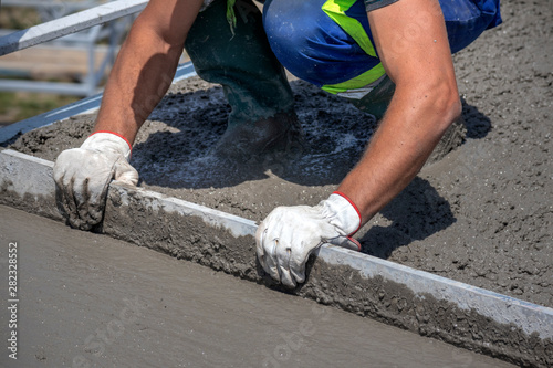 Worker straighten and smoothing fresh concrete on a construction site
