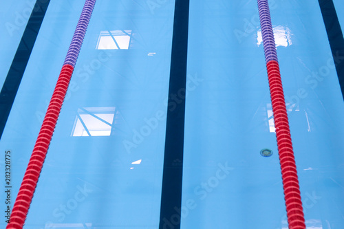 Empty swimming pool without people with quiet standing blue, clear water. Water sports in indoor pool. Swimming pool with marked colorful lanes.