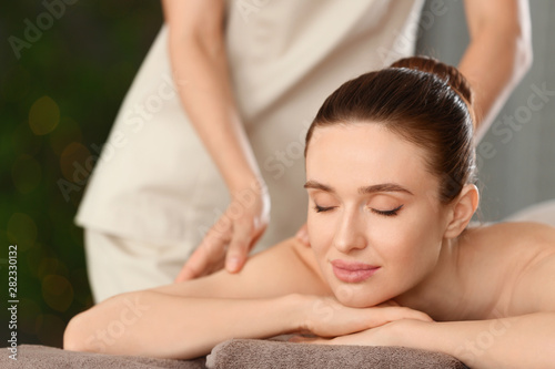 Beautiful young woman enjoying massage in spa salon