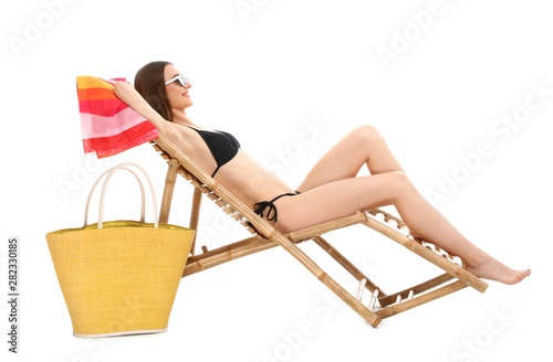 Fototapeta Young woman with beach accessories on sun lounger against white background