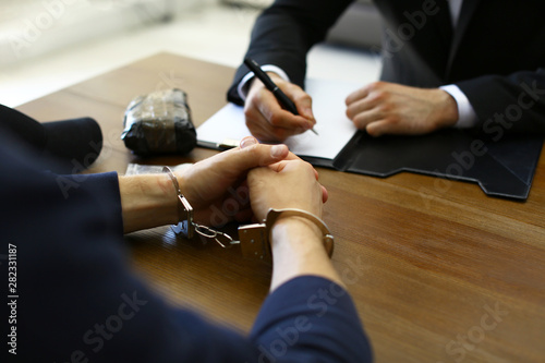 Canvas Print Police officer interrogating criminal in handcuffs at desk indoors