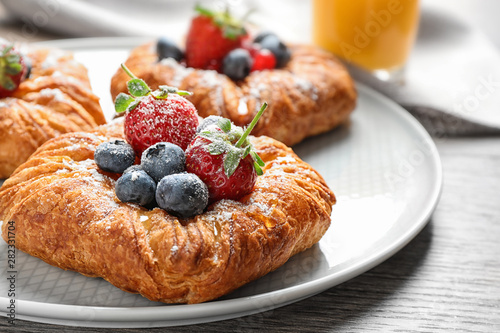 Fresh delicious puff pastry with sweet berries on wooden table, closeup