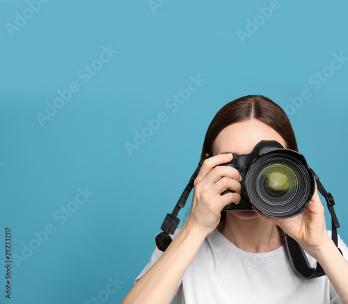 Professional photographer taking picture on light blue background. Space for text