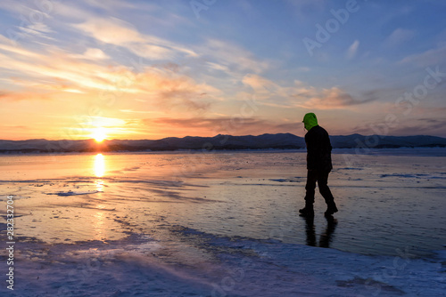 silhouette of man that are walking on the ice floor on the lake baikal with sunset.