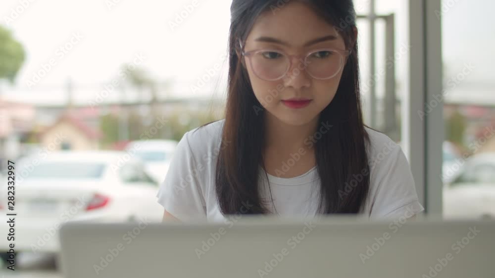 Freelance Asian women working on laptop at coffee shop. Young Asia business Girl using computer for trade, send email, digital work on internet on table at outdoor cafe in evening concept. Slow motion Freelance Asian women working on laptop at coffee shop. Young Asia business Girl using computer for trade, send email, digital work on internet on table at outdoor cafe in evening concept. Slow motion