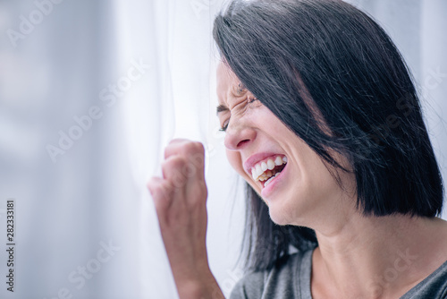 depressed brunette woman crying near window at home