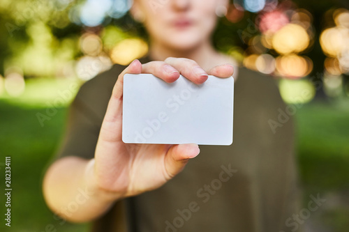 Girl holding a white credit card in her hands for shopping. 