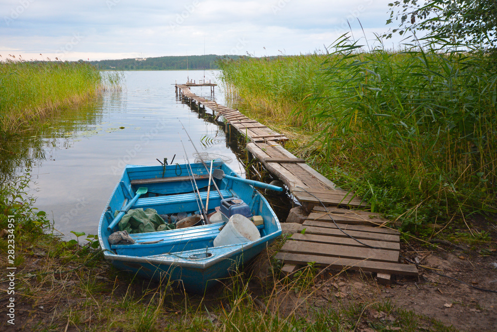 Fishing boat in a calm lake water.Old wooden fishing boat in a still lake water. Fishing boat in a calm lake water.Old wooden fishing boat in a still lake water.