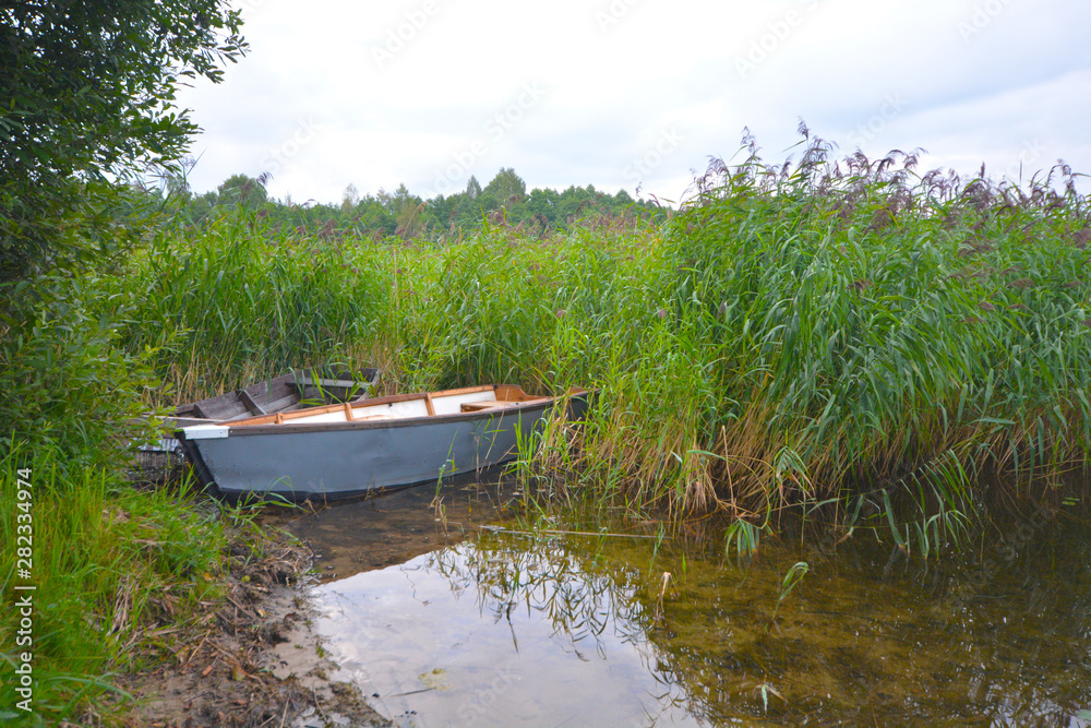 Fishing boat in a calm lake water.Old wooden fishing boat in a still lake water. Fishing boat in a calm lake water.Old wooden fishing boat in a still lake water.