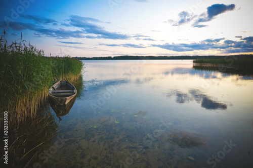 Fishing boat in a calm lake water.Old wooden fishing boat in a still lake water.