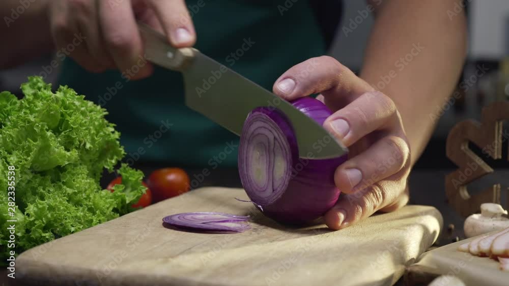Chef cuts the red onion by the sharp knife on the wooden board at the kitchen, close up video of cooking the vegetable salad, slicing the vegetables, Full HD Prores 422 HQ Chef cuts the red onion by the sharp knife on the wooden board at the kitchen, close up video of cooking the vegetable salad, slicing the vegetables, Full HD Prores 422 HQ