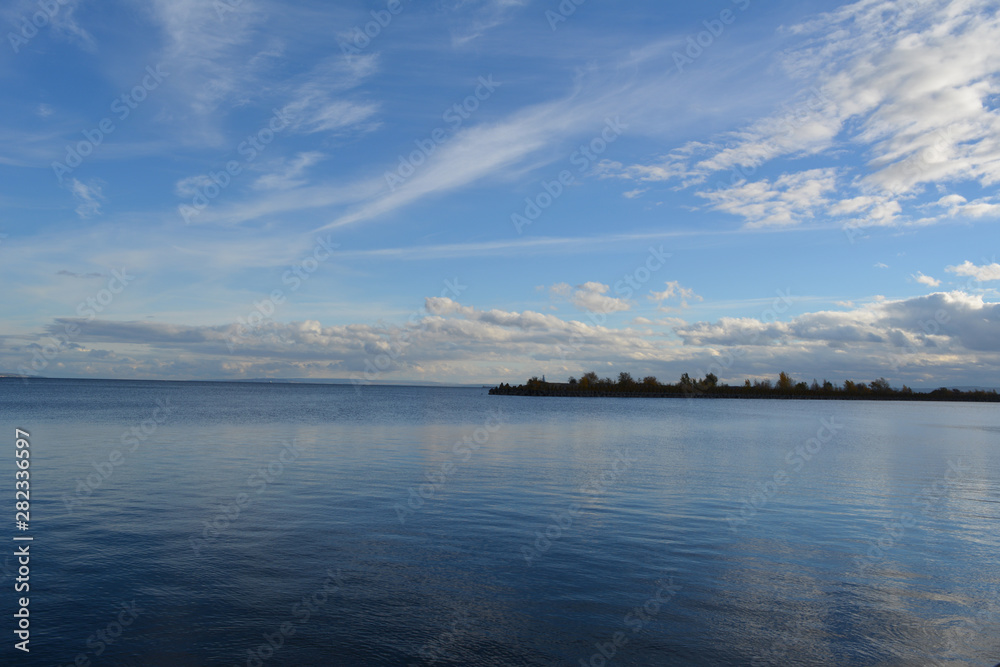 Fototapeta premium Picturesque landscape with blue river and light clouds in the sky. Panoramic view.