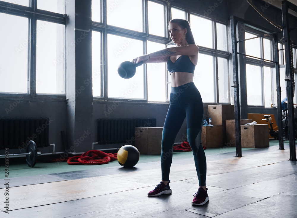 Young fitness female exercise with kettle bell. Caucasian woman