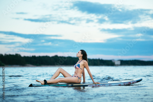 Beautiful fit surfing girl on surfboard on in the ocean. Woman ride good wave.