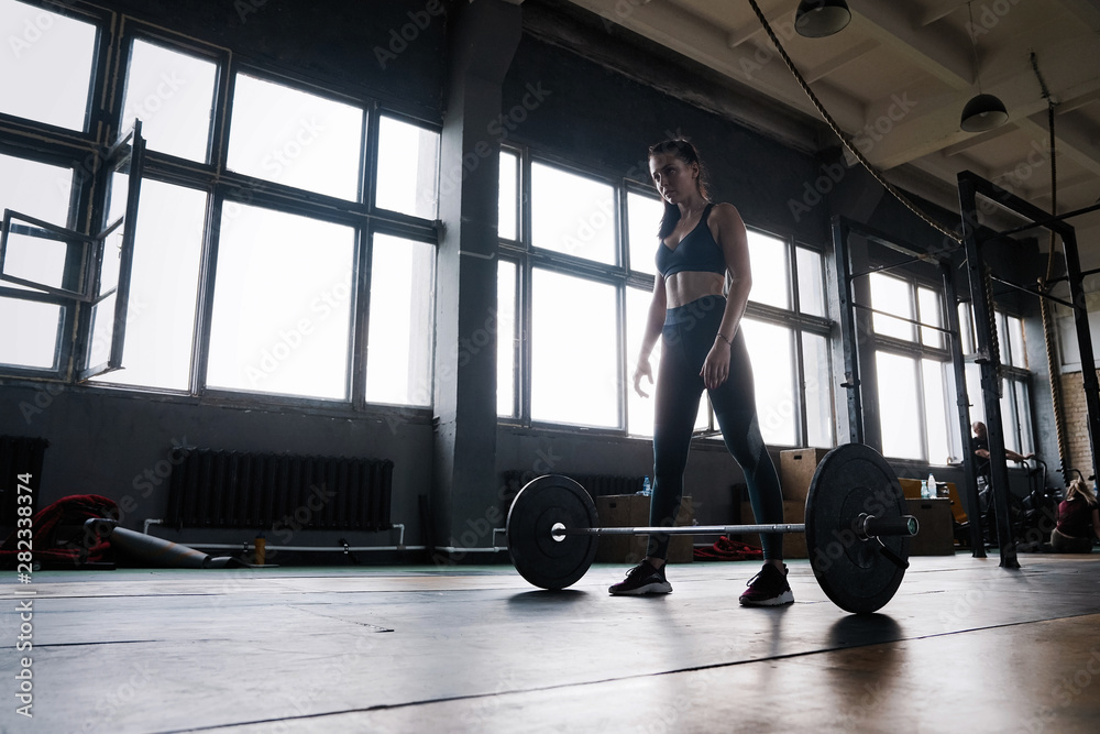 Attractive strong muscular female bodybuilder doing heavy duty squats lifting barbell at the crossfit gym Attractive strong muscular female bodybuilder doing heavy duty squats lifting barbell at the crossfit gym