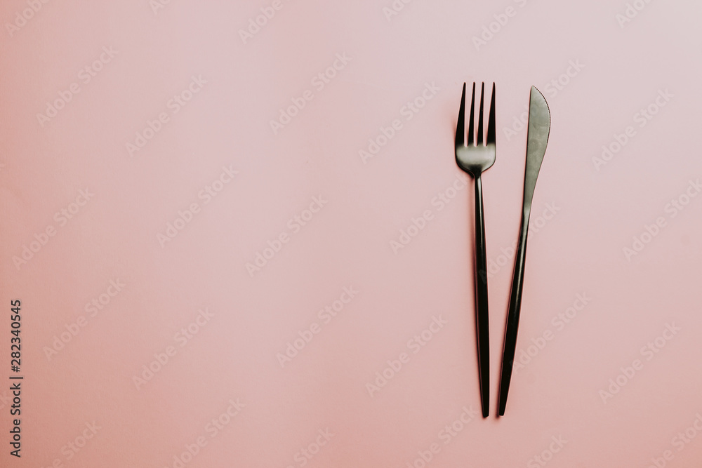 Black setting: plates, inen napkin and silverware on pink background. Top view. Black setting: plates, inen napkin and silverware on pink background. Top view.