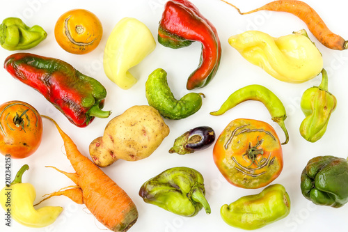 Trendy Ugly Organic Vegetables: potatoes, carrots, cucumber, peppers, chili, eggplant and tomatoes on white background, ugly food concept, top view, horizontal orientation