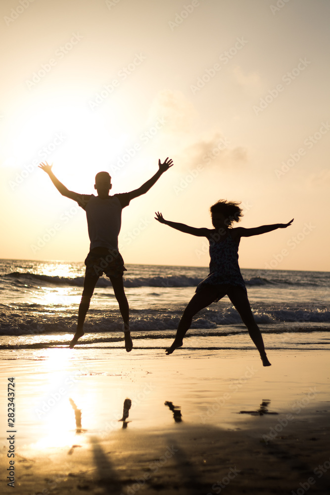 silhouette of two person jumping on the beach