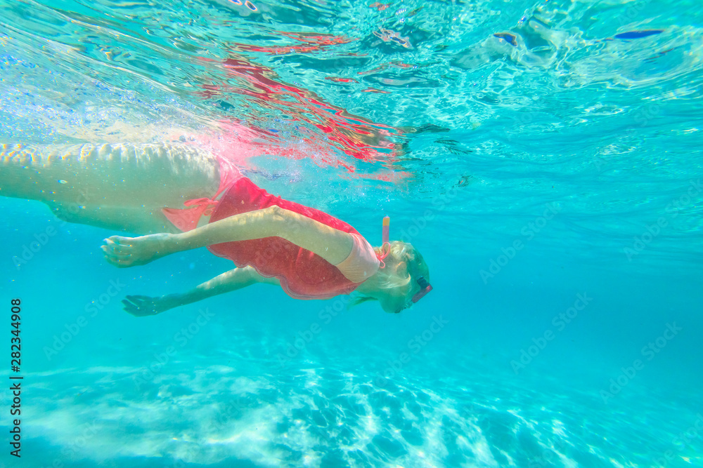 Woman free diving in clear waters of Greens Pool, William Bay NP. Female in apnea swims underwater with pink wetsuit. Denmark Region, Western Australia. Watersport activity in Australia.