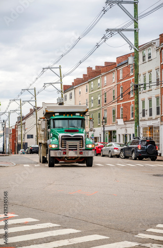 Green big rig tip truck running on the city street © vit