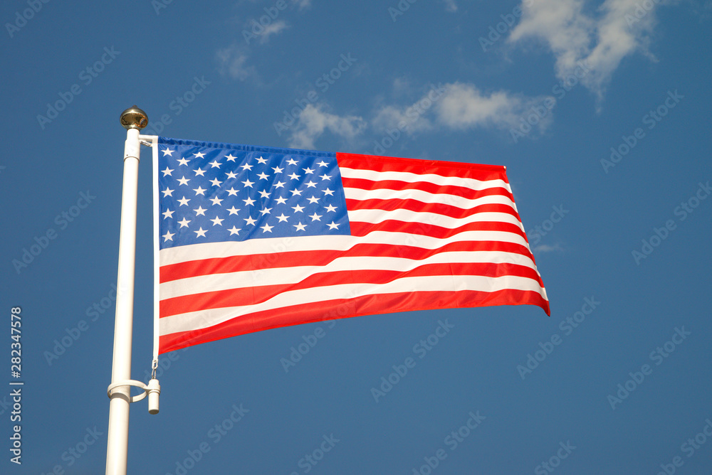 United States flag waving on the wind. Bright flag of America on the mast in sunny day and and blue skies. Bottom view.