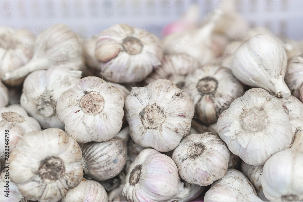 White garlic pile texture. Fresh garlic on market table closeup photo. Selective focus. White garlic pile texture. Fresh garlic on market table closeup photo. Selective focus.