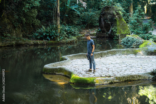 Handsome youth looks into coy pound in the Tijuca Rainforest. Rio de Janeiro, Brazil