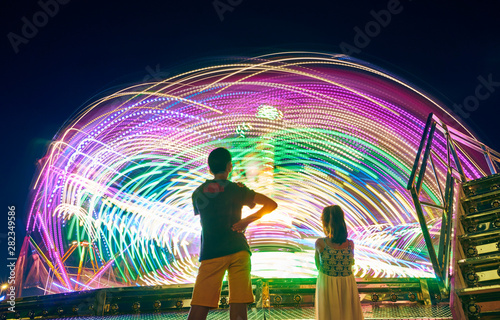 Children watching a fairground attraction at sunset. People enjoying the fairground attractions. photo