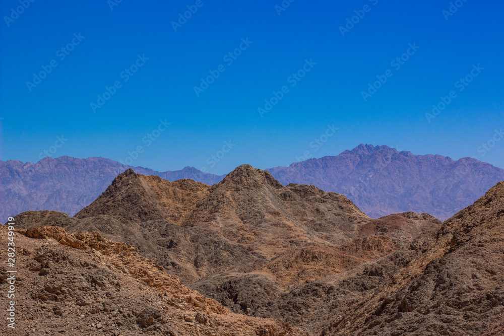 steep and sharp rocky mountain desert wilderness scenery landscape wallpaper pattern picture with empty blue sky background and space for copy or text 