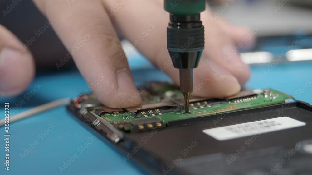 Smartphone assembling in repair shop. Screw in a screw. Mobile phone maintenance service Smartphone assembling in repair shop. Screw in a screw. Mobile phone maintenance service