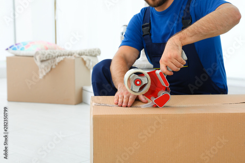 Young worker packing box in room, closeup. Moving service