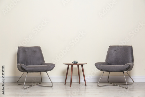 Tableau sur toile Room interior with modern chairs and table near light wall