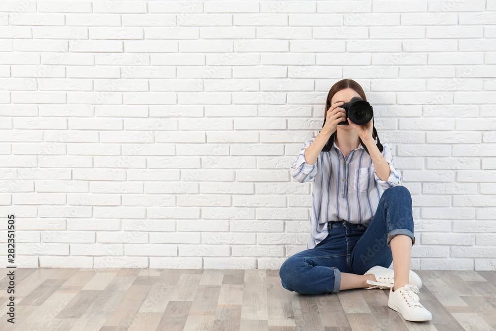 Professional photographer taking picture near white brick wall. Space for text