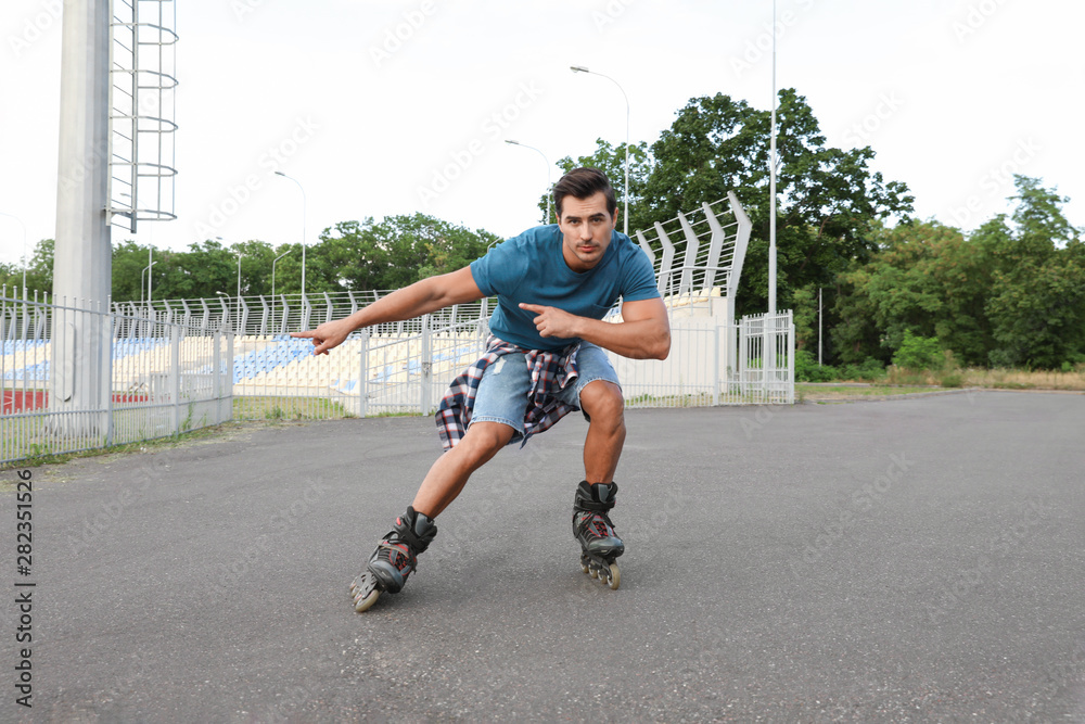Obraz premium Handsome young man roller skating outdoors. Recreational activity