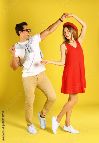 Beautiful young couple dancing on yellow background