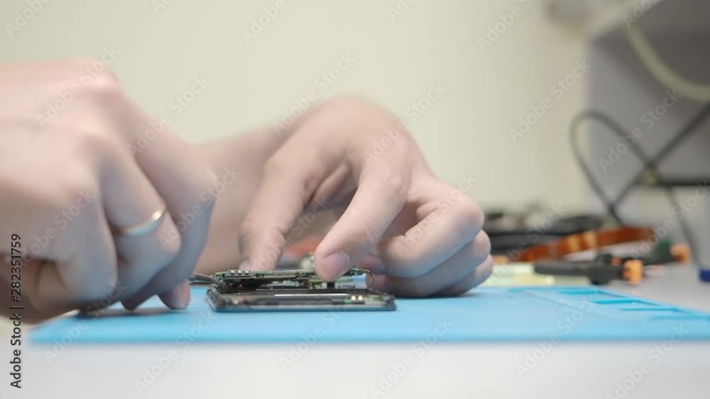 Smartphone assembling in repair shop. Connecting circuit and wires. Mobile phone maintenance service Smartphone assembling in repair shop. Connecting circuit and wires. Mobile phone maintenance service