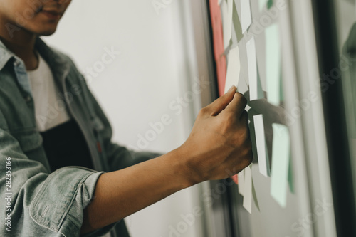 business people post it notes in glass wall at meeting room, teamwork concept