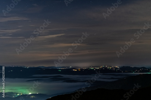 The view of the mountains surrounding Boone North Carolina at night with low lying cloud inversion and glowing city lights