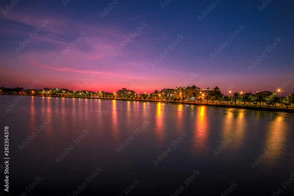 Blurred wallpaper of colorful, twilight sky by the sea, with lights from the street shining at night, beautiful natural occurrences, seen in scenic spots or tourist attractions. B  โดย Bangprikphot