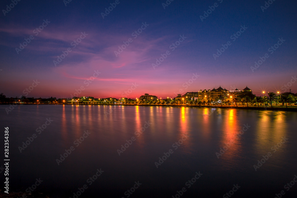 Blurred wallpaper of colorful, twilight sky by the sea, with lights from the street shining at night, beautiful natural occurrences, seen in scenic spots or tourist attractions. B  โดย Bangprikphot
