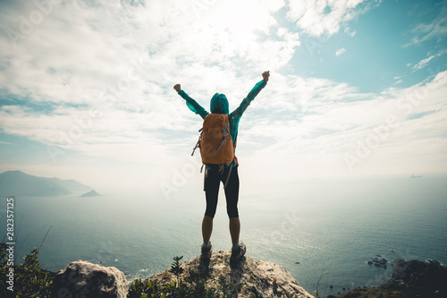 Successful hiker outstretched arms at seaside mountain top cliff edge photo