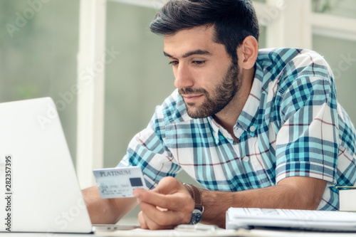 businessman working at home using laptop and holding credit card making online payment