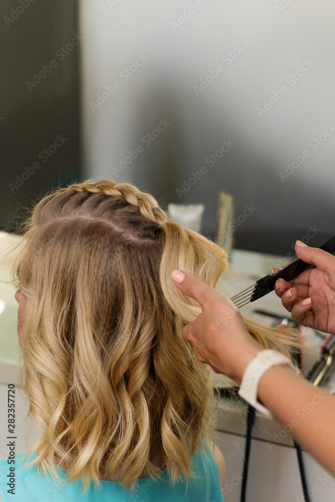 Fototapeta premium Barber braids high braid. Hairdressing services. Creating evening hairstyles fashionable stylish women's hairstyles. Process of hair styling. Courses in hairdressing. Beauty salon concept.