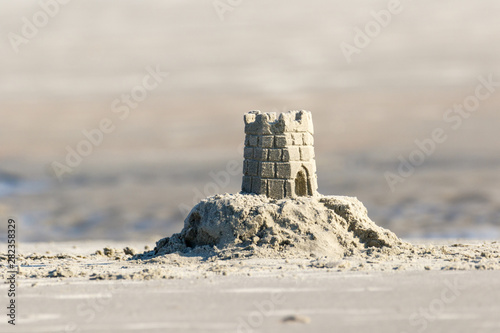 Detailed sand castle on the beach with a tidal pool in the background